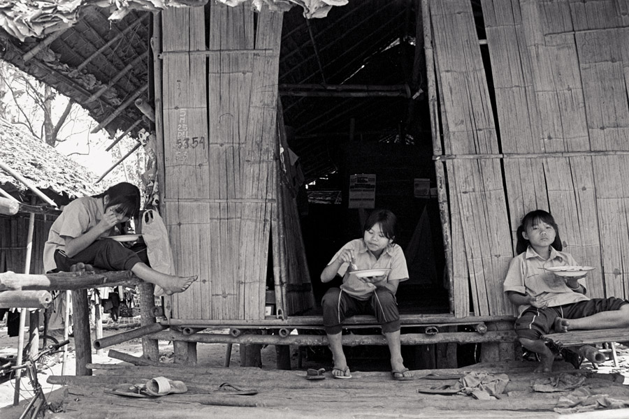 Rocky Mountain School: students eat lunch outside their dorms. Dorm styles vary widely at schools along the Thai-Burma border. Many are simple bamboo stilt-houses like these.
