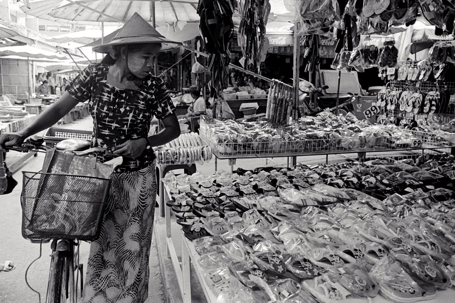 2011: young woman wearing thanaka (traditional cosmetic made of powdered tree bark) peruses the market.